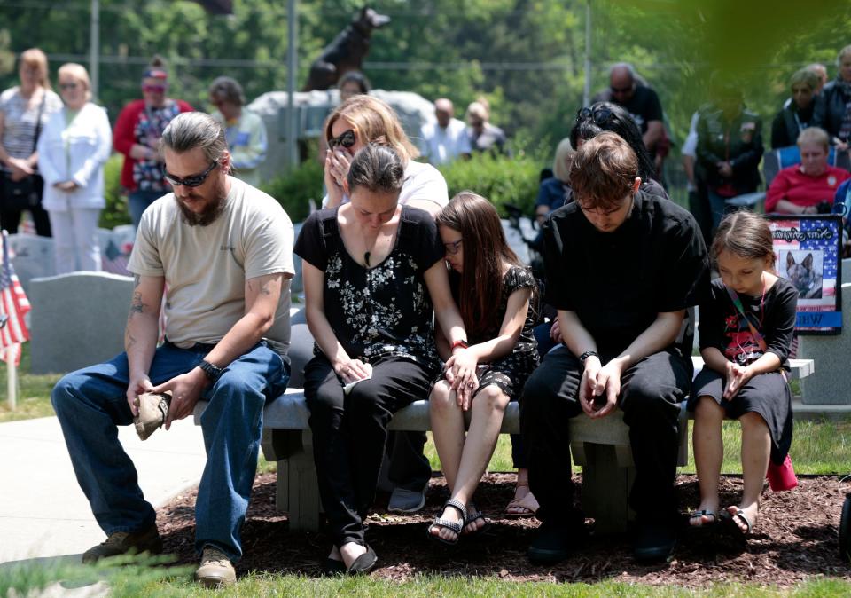 John Van Dyk, left, prays with his wife, Kelli Van Dyk ,and their kids Breana, Draven and McKensie while remembering Lucky6, the military war dog that served with him during a memorial service at the Michigan War Dog Memorial in South Lyon on June 17, 2023.