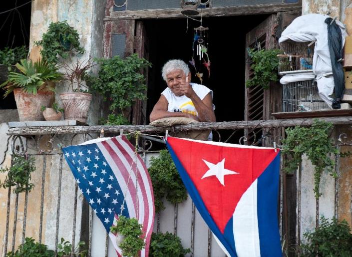 A Cuban gives the thumbs up from his balcony decorated with the US and Cuban flags in Havana, on January 16, 2015 (AFP Photo/Yamil Lage)
