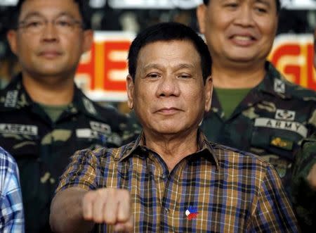 Philippine President Rodrigo Duterte makes a "fist bump", his May presidential elections campaign gesture, with soldiers during a visit at Capinpin military camp in Tanay, Rizal in the Philippines August 24, 2016. REUTERS/Erik De Castro