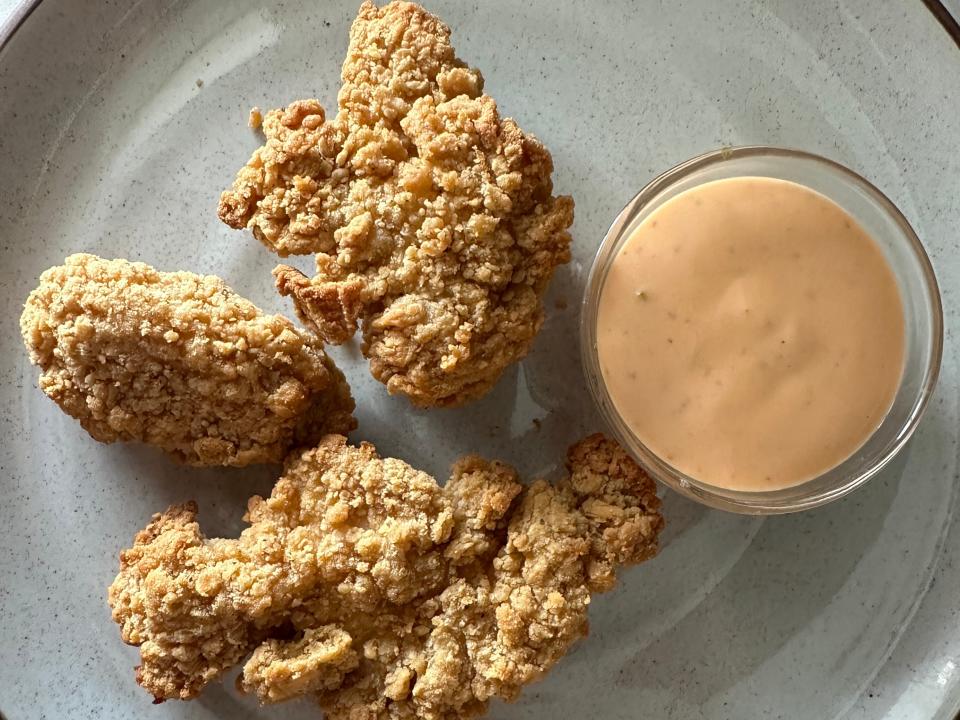 plate of chicken tenders with sauce on the side