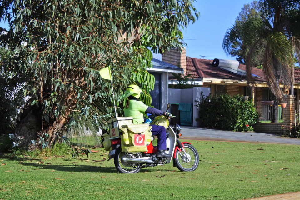 Australia Post postman delivering mail on a moped bike