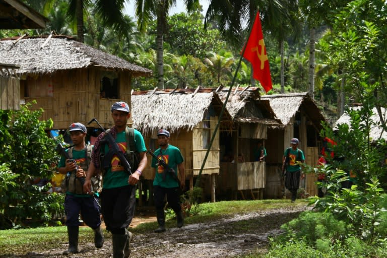 Members of the communists' armed wing, the New People's Army (NPA), walk past a hammer and sickle flag displayed in a village as they mark the 46th anniversary of its founding, on the southern island of Mindanao on December 26, 2014