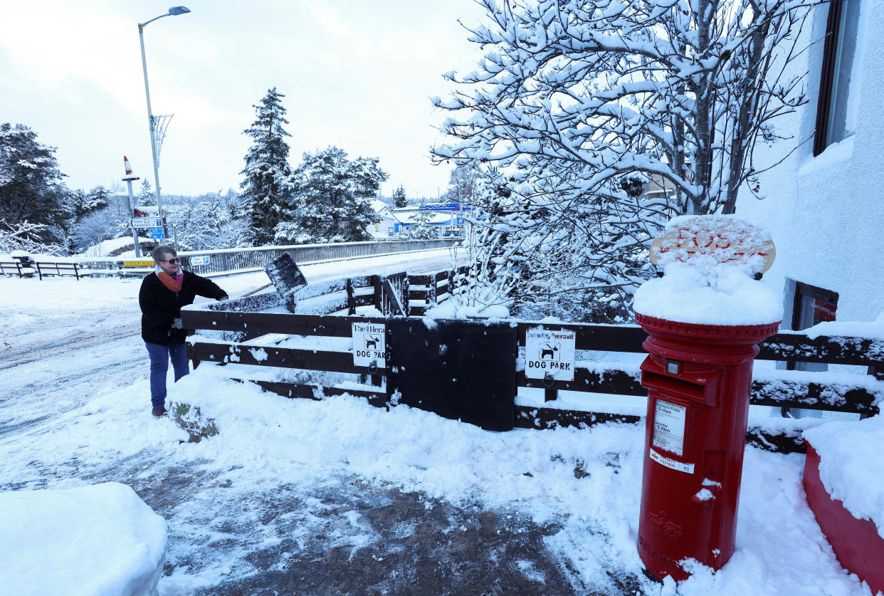 A woman shovels snow in Carrbridge Scotland, Britain January 18, 2023. REUTERS/Russell Cheyne