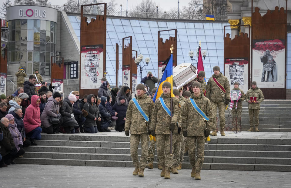 People kneel as the Ukrainian servicemen carry the coffin of their comrade Oleh Yurchenko killed in a battlefield with Russian forces in Donetsk region during a commemoration ceremony in Independence Square in Kyiv, Ukraine, Sunday, Jan. 8, 2023. (AP Photo/Efrem Lukatsky)