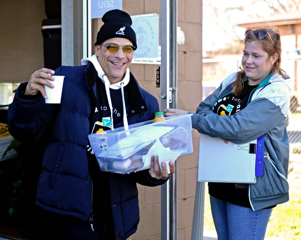 Lindsay Frelka holds the door open for Lawrence Harris as they head out to a neighborhood to canvass at the Service Employees International Union November 18, in Milwaukee.