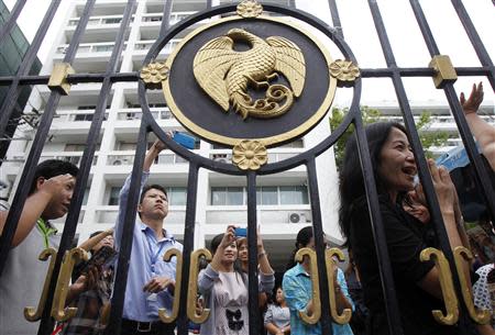 Thailand's Finance Ministry officers stand behind the ministry's gate while anti-government protesters rally outside in central Bangkok April 2, 2014. Gunmen opened fire on a group of Thai anti-government protesters driving away from a Bangkok rally on Tuesday, killing one, wounding four and raising tension in a political crisis that has gripped the country for months. REUTERS/Chaiwat Subprasom