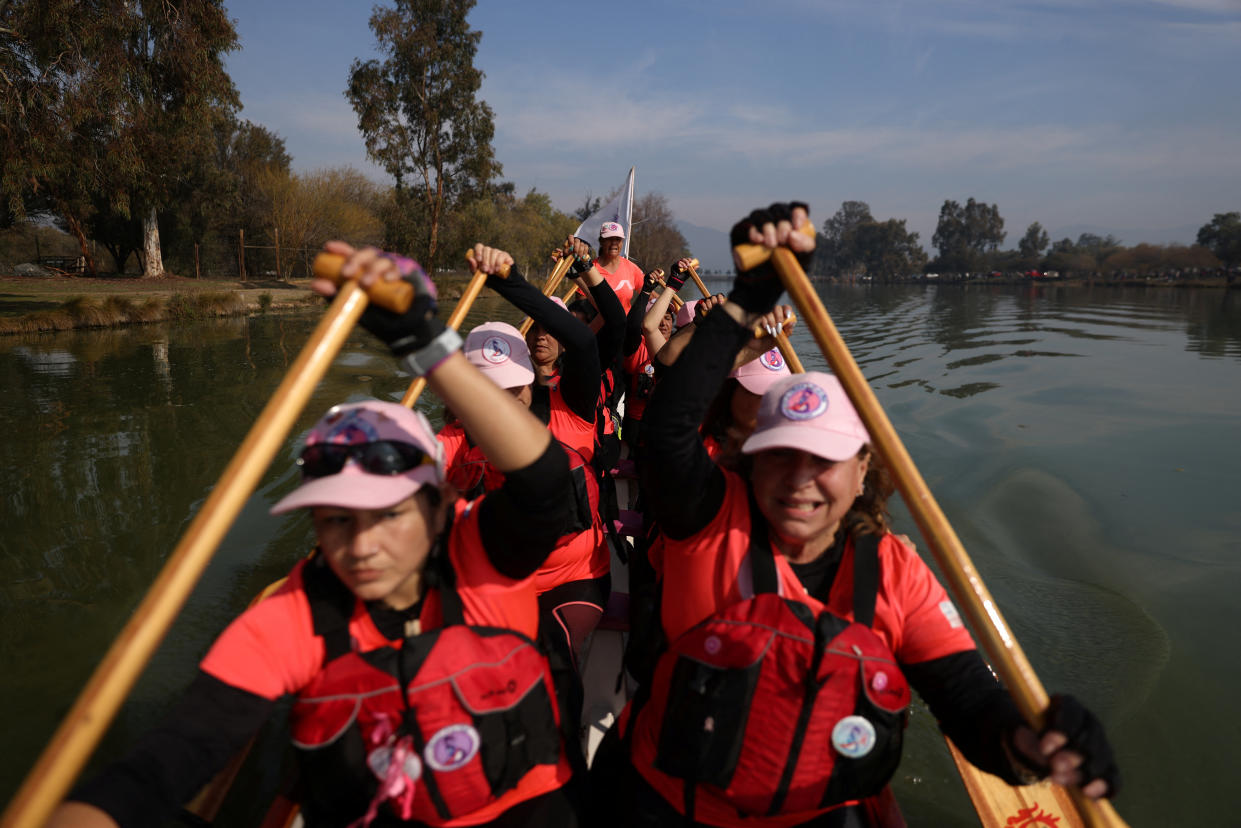 Miembros de un equipo de remo de botes dragón para mujeres con cáncer de mama y sobrevivientes reman durante una sesión de entrenamiento en una laguna en las afueras de Santiago, Chile, el 24 de julio de 2022. (REUTERS/Ivan Alvarado)