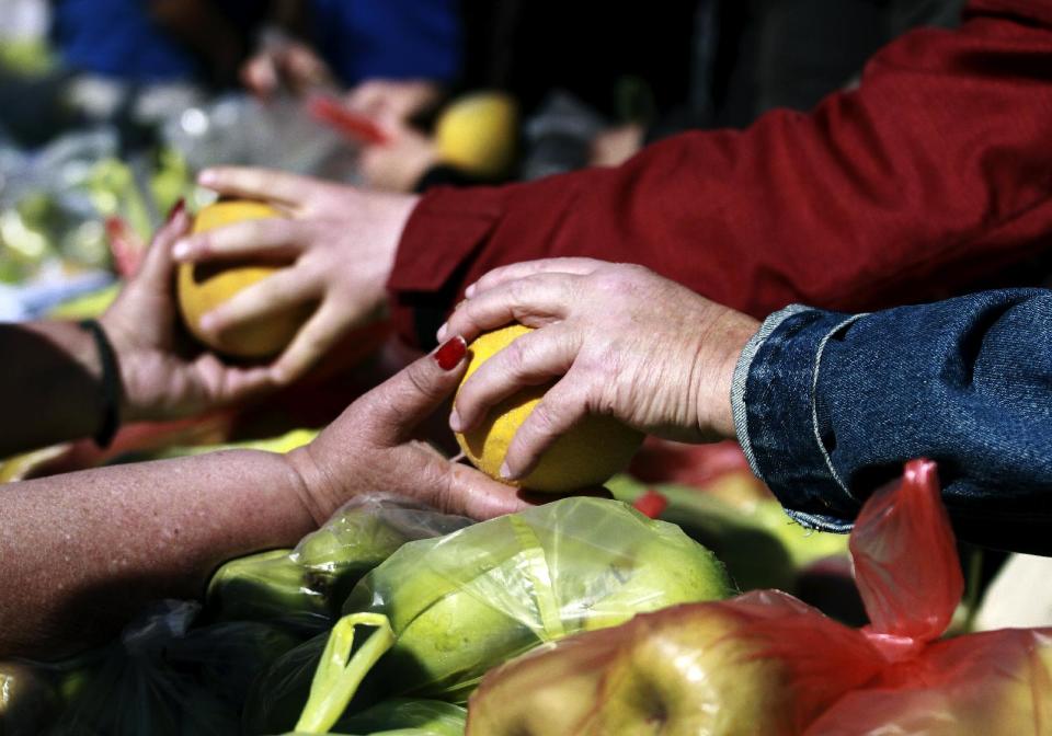 Greek farmers' market vendors distribute free produce as part of a protest in Athens, Wednesday, April 30, 2014, after their trading association launched an indefinite strike Monday. The market vendors are the latest professional group in Greece to protest a sweeping liberalization drive demanded by rescue creditors. (AP Photo/Dimitri Messinis)