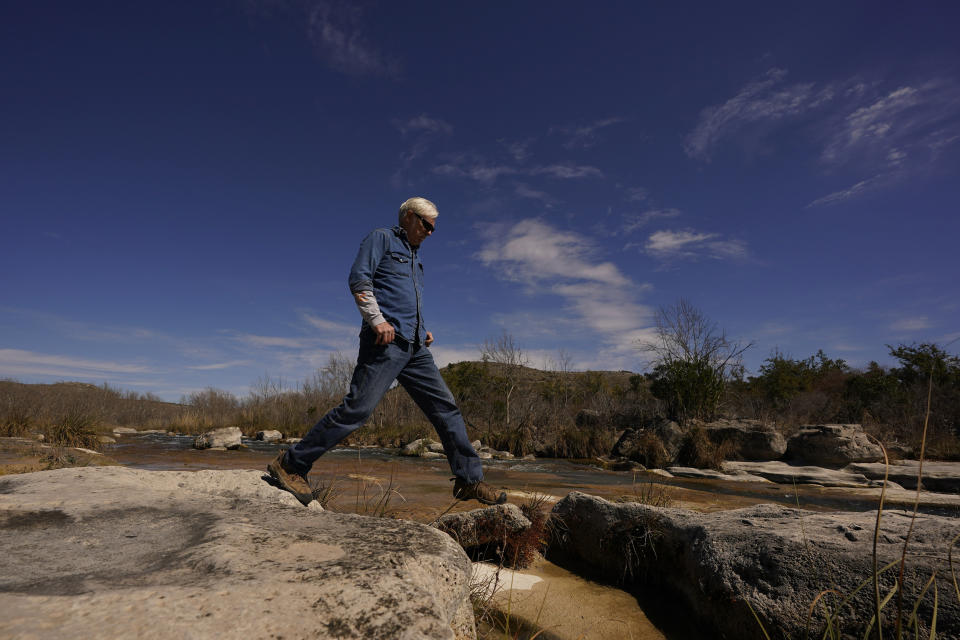 Rancher Randy Nunns walks along the Devil's River near Del Rio, Texas, Thursday, Feb. 16, 2023. Nunns and fellow landowners along the Devil's River argue that proposed wind turbines would kill birds, bats and disrupt monarch butterflies migrating to Mexico and impact ecotourism, a main source of income for many. (AP Photo/Eric Gay)