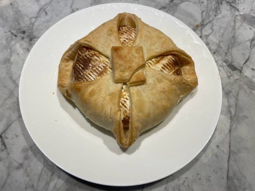 Golden-brown baked Brie wrapped in pastry on a white plate