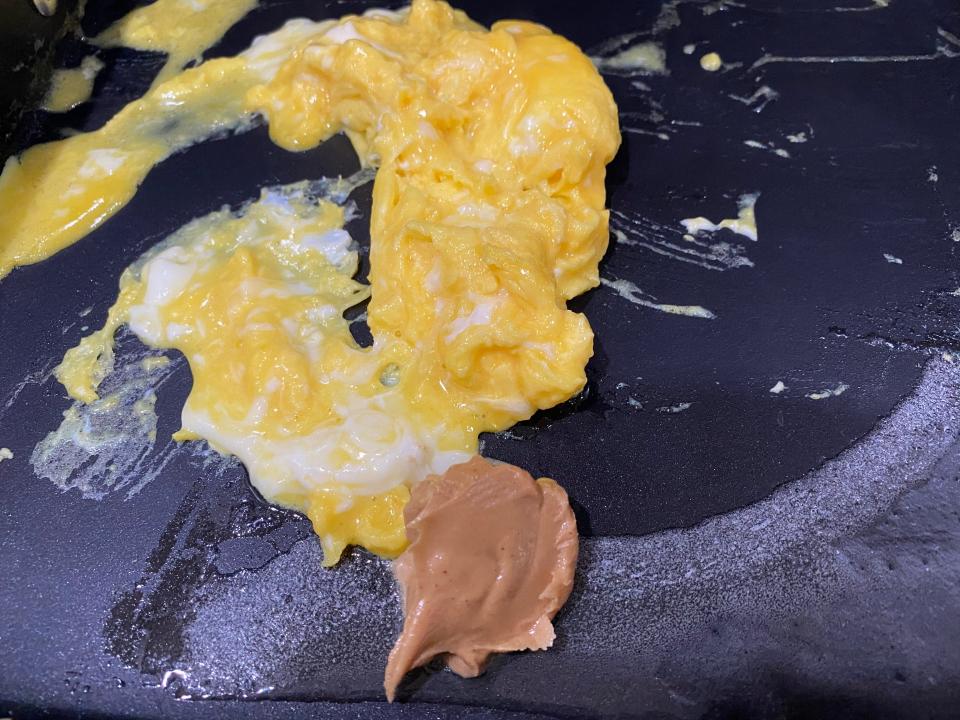 a glob of peanut butter in a pan with scrambled eggs