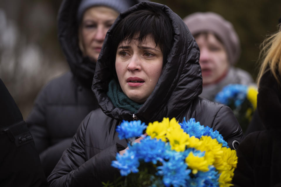 巴赫姆特戰事激烈，一名烏克蘭女性手捧花束追悼在戰火中的罹難者。(畫面來源：AP)