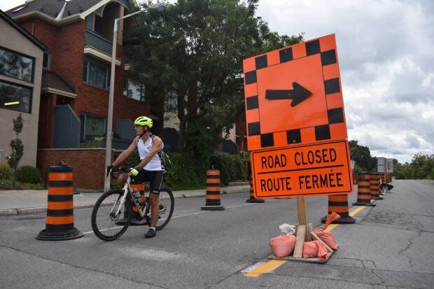 A man stops his bike at the intersection of Hawthorne and Colonel By Drive on Monday - the last day before a five-kilometre stretch of Colonel By reopens to motor vehicles. (Ben Andrews/CBC News - image credit)