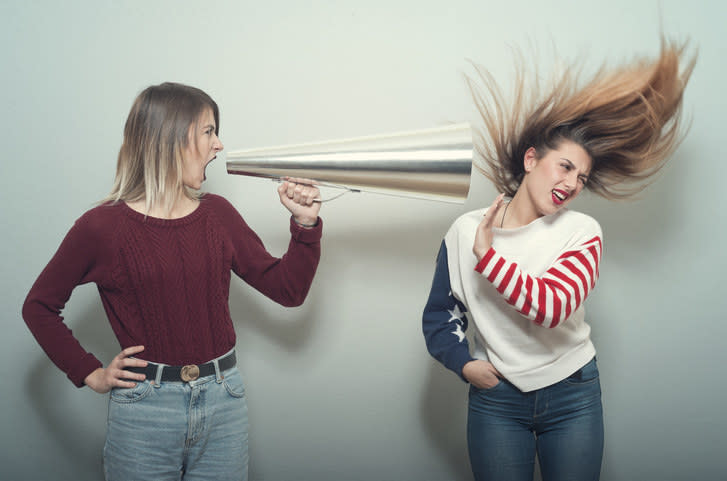 a woman screaming into a megaphone into another woman's ear