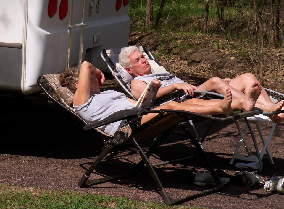 This May 2014 photo shows Patricia Zwart of Larchwood, Iowa, reading a book while her husband relaxes next to their camper in Palisades State Park in South Dakota near the Minnesota border. The Zwarts are among a number of Americans enjoying early season camping after a brutal winter. South Dakota's Division of Parks and Recreation says camping reservations are up this year. (AP Photo/Joe Kafka)