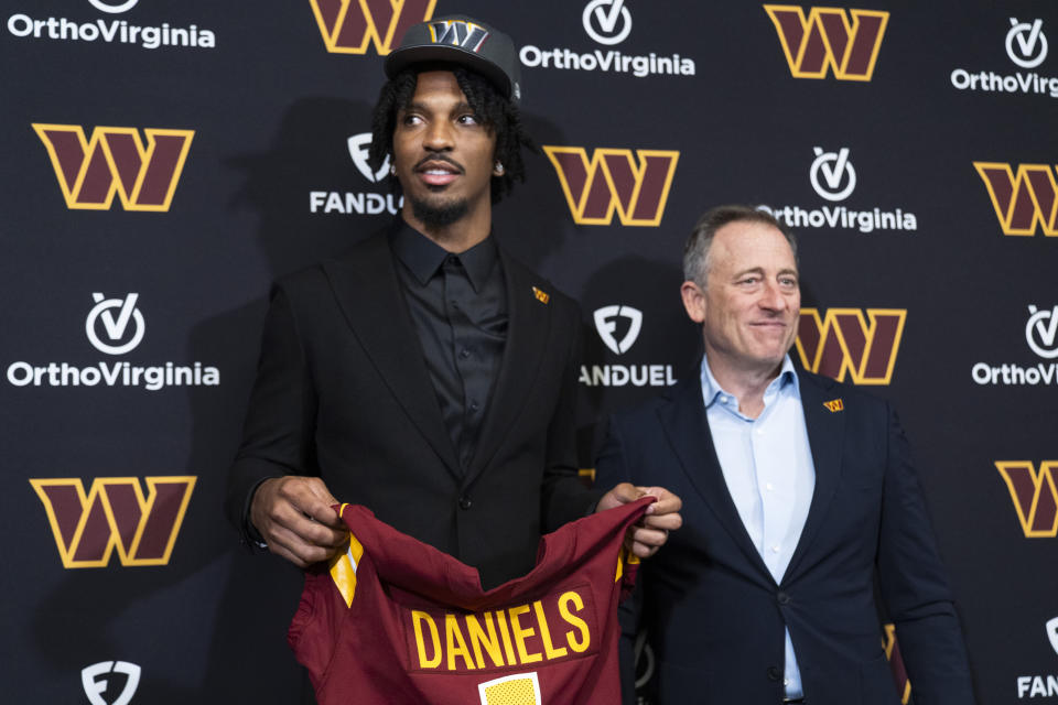 Washington Commanders irst round draft pick Jayden Daniels, left, holds his jersey with controlling owner Josh Harris, right, following an NFL football news conference in Ashburn, Va., Friday, April 26, 2024. (AP Photo/Manuel Balce Ceneta)