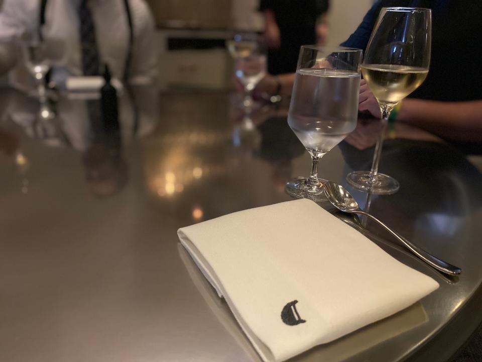 a simple place setting on a metal table with a napkin and glass