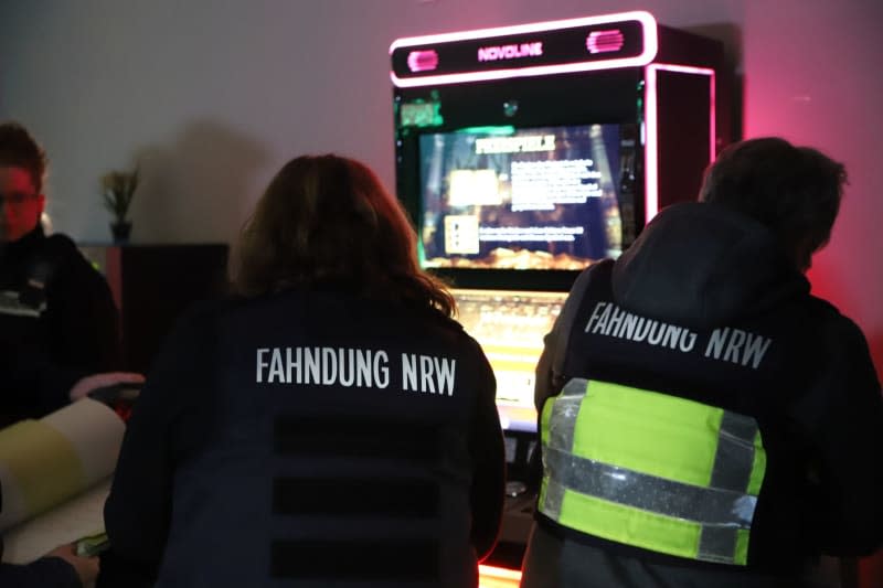 Employees of the NRW tax investigation department stand by gambling machines during a search of a gambling hall. Police, customs, the public order office and the tax investigation department jointly searched premises in Duisburg under suspicion of illegal gambling under the watchful eye of NRW Interior Minister Reul. -/dpa