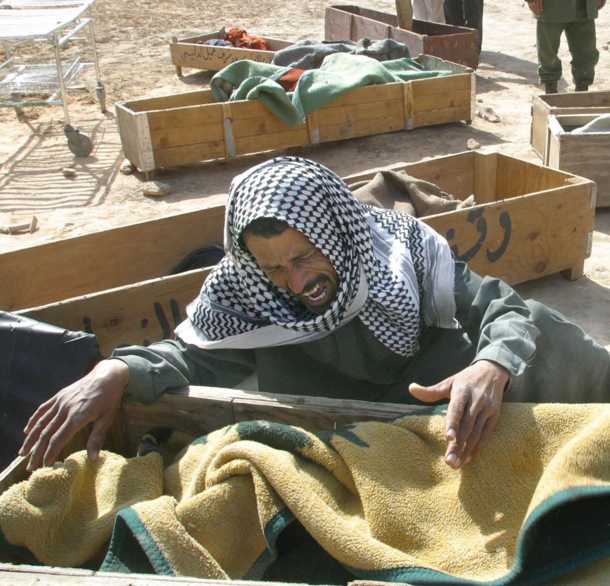 Razzaq Kazem al-Khafaj grieves over the body of his mother in Hilla in the southern province of Babylon on April 1, 2003. Khafaj lost 15 members of his family including six children, as his car was bombed by coalition helicopters while fleeing al-Haidariyeh towards Babylon. Thirty-three civilians were killed and 310 wounded in a U.S.-British coalition bombing of the residential area of Nader south of the city of Hilla, 50 miles south of Baghdad.