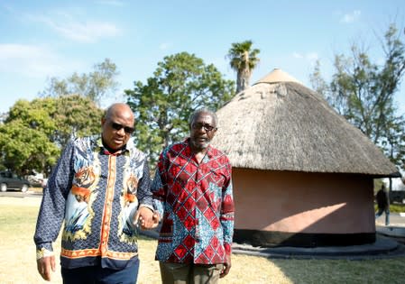 Former Zimbabwe President Robert Mugabe's nephews Leo Mugabe and Philip Chiyangwa hold hands as they walk at their uncle's rural homestead in Kutama