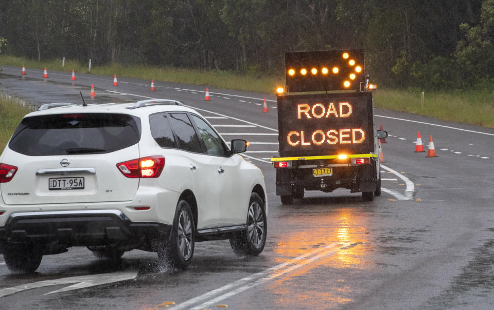 A vehicle is diverted as a road is closed due to flooding on the outskirts of Port Stephens, 200 kilometers (120 miles) north of Sydney, Australia, Sunday, March 21, 2021. Residents across the state of New South Wales have been warned to prepare for possible evacuations, as NSW Premier Gladys Berejiklian said the state's flood crisis would continue for several more days. (AP Photo/Mark Baker)