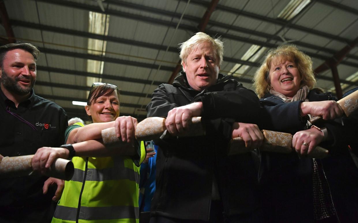 Boris Johnson pulls Christmas crackers with staff members during a visit to IG Design Group - Ben Stansall/AP