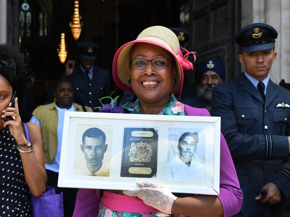 <p>Andria Marsh holds up photographs of her parents and her original British passport after a service at Westminster Abbey in celebration of 70 years since the arrival of Empire Windrush, 22 June 2018</p> (EPA-EFE)