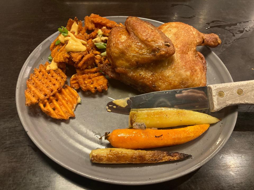 Butcher & Sprout's roasted half-chicken, smothered in thyme butter and served with rainbow carrots and sweet potato waffle fries.