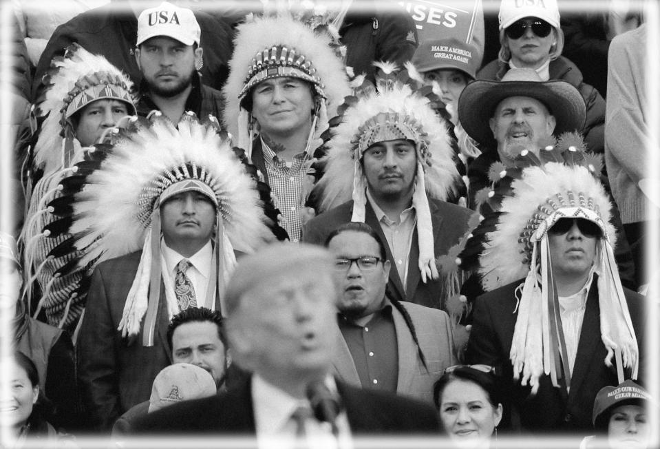 A group of Native Americans wearing traditional headdresses listen as President Donald Trump speaks during a campaign rally for Republican U.S. Senate candidate Matt Rosendale in Belgrade, Montana in 2018. (Photo: Carlos Barria/Reuters; digitally enhanced by Yahoo News)