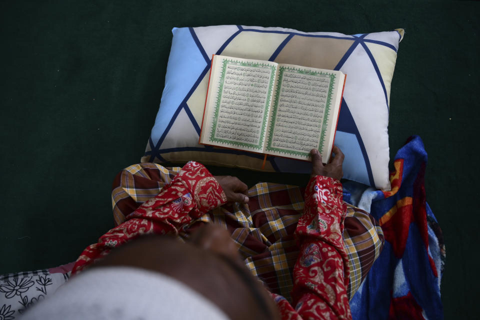 Bashir Ahmed, a Rohingya survivor of a capsized refugee boat, reads the Quran at his temporary shelter in Meulaboh, Indonesia, on Thursday, April 4, 2024. Bashir was among 75 people rescued from atop the overturned hull of the boat, which capsized off Indonesia's coast in March. Dozens of others died. (AP Photo/Reza Saifullah)