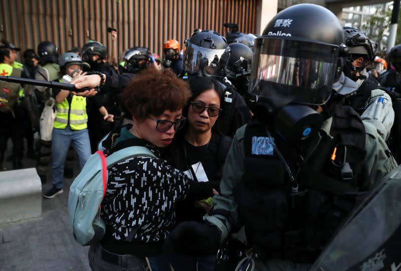 Protesters stand next to riot police officers during the "Lest We Forget" rally in Hong Kong