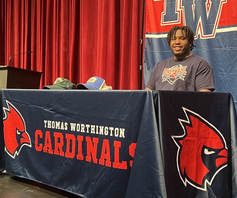 With caps from Michigan State and Pittsburgh on the table in front of him, Thomas Worthington senior defensive tackle Francis Brewu awaits his signing ceremony Wednesday. Brewu signed a letter of intent with Pittsburgh.