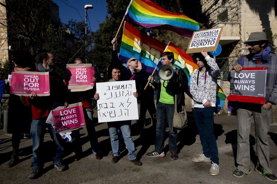 Israeli activists hold signs as they protest against Russia's human rights record and anti-gay law in front of Israel's President Shimon Peres' residence during the visit of Dmitry Kiselyov, head of Russia Today, Russia's largest news agency, in Jerusalem, Wednesday, Feb. 5, 2014. The law bans pro-gay "propaganda" that could be accessible to minors. Activists view the law as forbidding almost any public expression of gay-rights sentiment. Hebrew sign, center, reads, "homophobe and racist not in the presidents' residence," referring to the visitor. (AP Photo/Sebastian Scheiner)