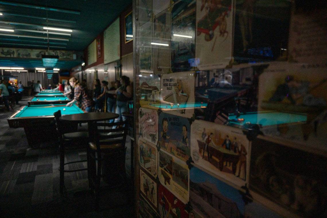Vintage billiard postcards line a wall at a Jointed Cue Billiards in Hollywood Park while patrons play pool Thursday.