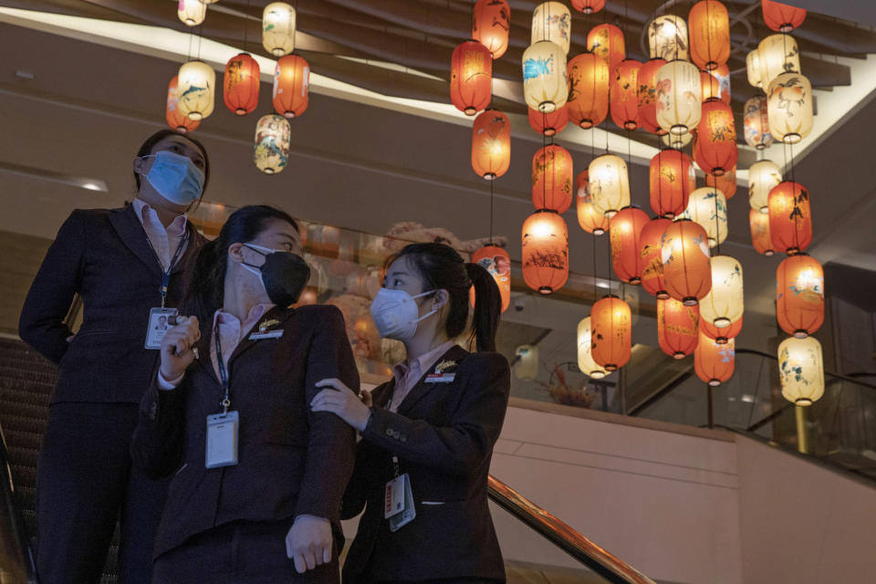 Office workers wearing mask against coronavirus move past lantern decorations in a mall and office building in Beijing on Thursday, March 19, 2020. China has only just begun loosening draconian travel restrictions within the country, but has stepped-up 14-day quarantine regulations on those arriving in Beijing, Shanghai and elsewhere from overseas, amid expectations of a new influx of students and others returning home. (AP Photo/Ng Han Guan)