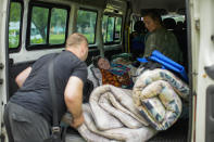 Two women are carried from their homes in an evacuation by British volunteers group BEAR in Bakhmut, eastern Ukraine, Friday, May 27, 2022. Volunteers have been racing to evacuate as many civilians as possible, particularly the elderly and those with mobility issues, as Russian forces make advances in the region. (AP Photo/Francisco Seco)