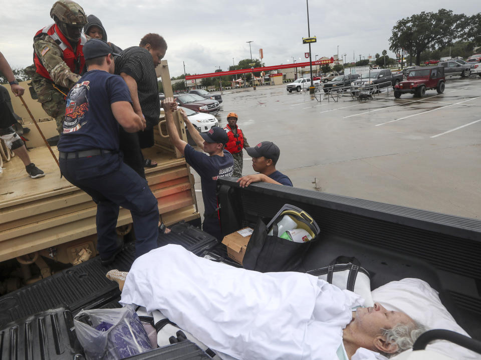 Dwain Kaufman, right, waits for his wife as she is helped into the back of a family member's truck by Beaumont firefighters and members of the Texas National Guard on Thursday, Sept. 19, 2019, in Beaumont, Texas. The remnants of Tropical Storm Imelda unleashed torrential rains in parts of Texas, prompting hundreds of water rescues, a hospital evacuation and road closures as the powerful storm system quickly drew comparisons to 2017's Hurricane Harvey. (Jon Shapley/Houston Chronicle via AP)