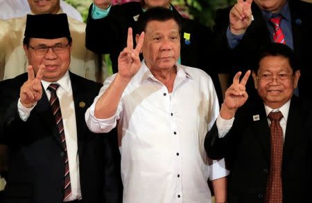 Philippine President Rodrigo Duterte (C) with Moro Islamic Liberation Front (MILF) chairperson Al Haj Murad Ebrahim (L) and Ghazali Jaafar, MILF vice-chairman flash a "V" sign during a handover of a draft law of the Bangsamoro Basic Law (BBL) in a ceremony at the Malacanang presidential palace in metro Manila, Philippines July 17, 2017. REUTERS/Romeo Ranoco