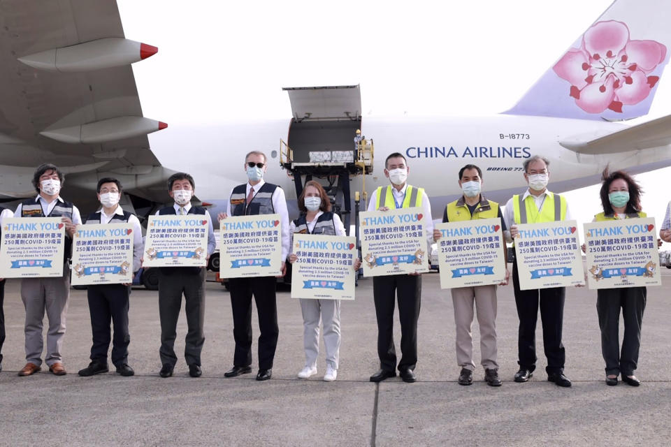 In this photo released by the Taiwan Centers for Disease Control, Taiwan's Health Minister Chen Shih-chung, third from left, and Brent Christensen, the top U.S. official in Taiwan, fourth from left, hold up thank you cards as they welcome a China Airlines cargo plane carrying COVID-19 vaccines from Memphis that arrived at the airport outside Taipei in Taiwan on Sunday, June 20, 2021. The U.S. sent 2.5 million doses of the Moderna COVID-19 vaccine to Taiwan on Sunday, tripling an earlier pledge in a donation with both public health and geopolitical meaning. (Taiwan Centers for Disease Control via AP)