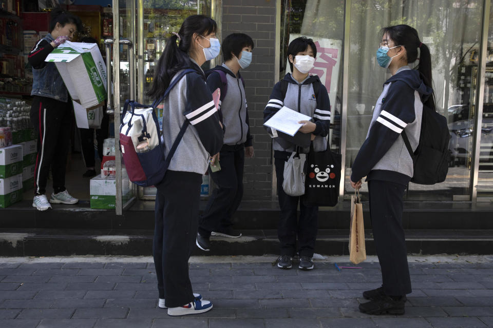 Students, wearing face masks, chat before attending school near a middle school in Beijing on Monday, May 11, 2020. The Chinese capital partially reopen schools for some students on Monday as authorities push to restore normalcy after the lockdown to fight the coronavirus. (AP Photo/Ng Han Guan)