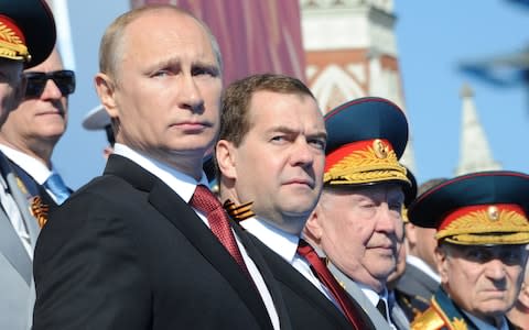 Russia's President Vladimir Putin (L) and Prime Minister Dmitry Medvedev (2nd L) attend a Victory Day parade at the Red Square in Moscow - Credit: MIKHAIL KLIMENTYEV/AFP/Getty Images