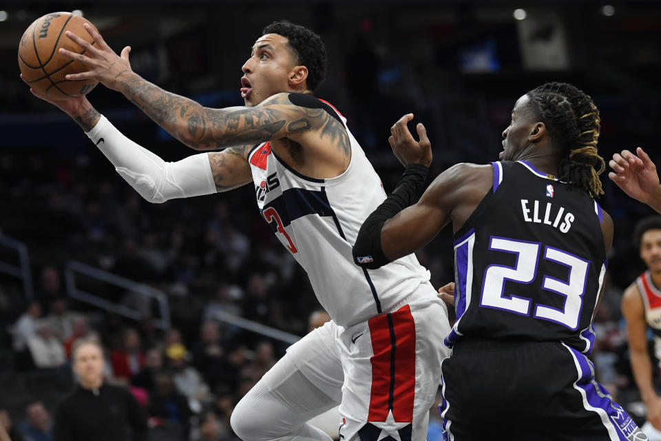 Washington Wizards forward Kyle Kuzma, left, drives past Sacramento Kings guard Keon Ellis for a score during the first half of an NBA basketball game Thursday, March 21, 2024, in Washington. (AP Photo/John McDonnell)