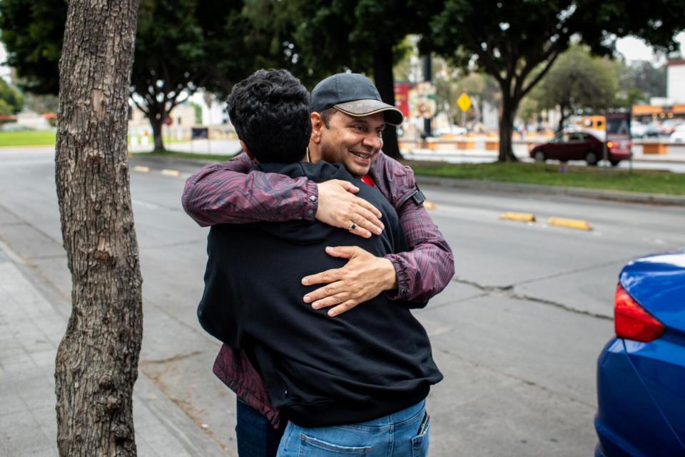 Dr. Pradyuman Singh hugs his son on a sidewalk