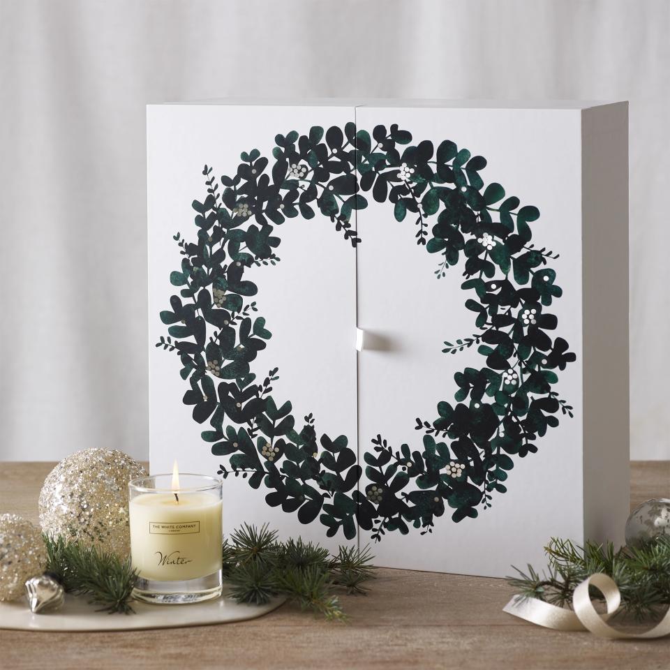 The White Company's advent calendar for 2023 located on a table with Christmas decorations.