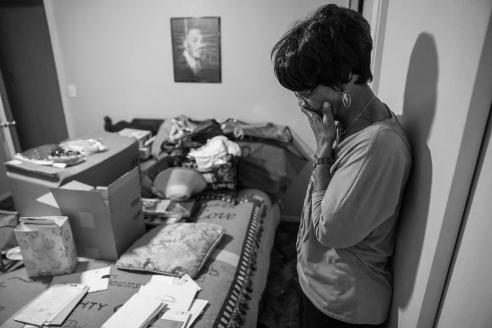 A woman, looking at envelopes and other items, holds her hand to mouth in thought.