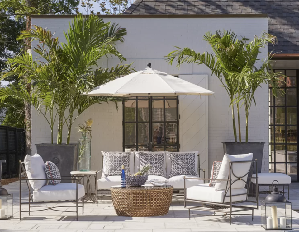 a patio with a white umbrella and chairs