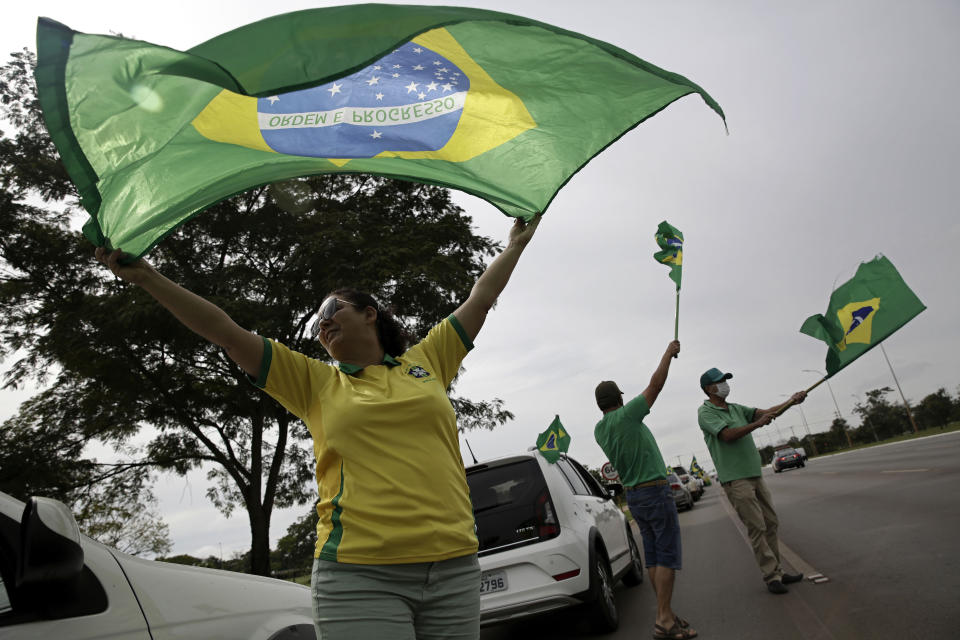 People wave national flags during a demonstration backing President Jair Bolsonaro’s anti-coronavirus-lockdown stance, marking May Day, or International Workers' Day, in Brasilia, Brazil, Saturday, May 1, 2021. (AP Photo/Eraldo Peres)