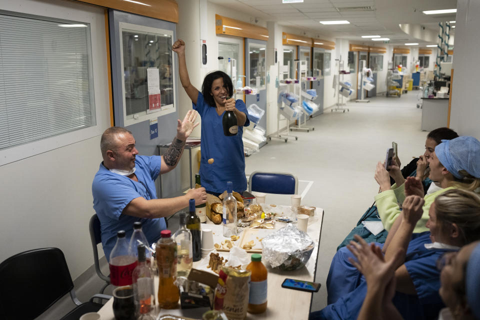 Nurse Bess Tribout, center, pops champagne to celebrate the new year in the COVID-19 intensive care unit at the la Timone hospital in Marseille, southern France, Saturday, Jan. 1, 2022. (AP Photo/Daniel Cole)