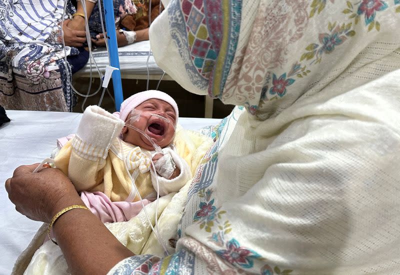 One-month old baby girl, Noor cries while being comforted by her grandmother inside the paediatric ward at Sir Ganga Ram hospital in Lahore