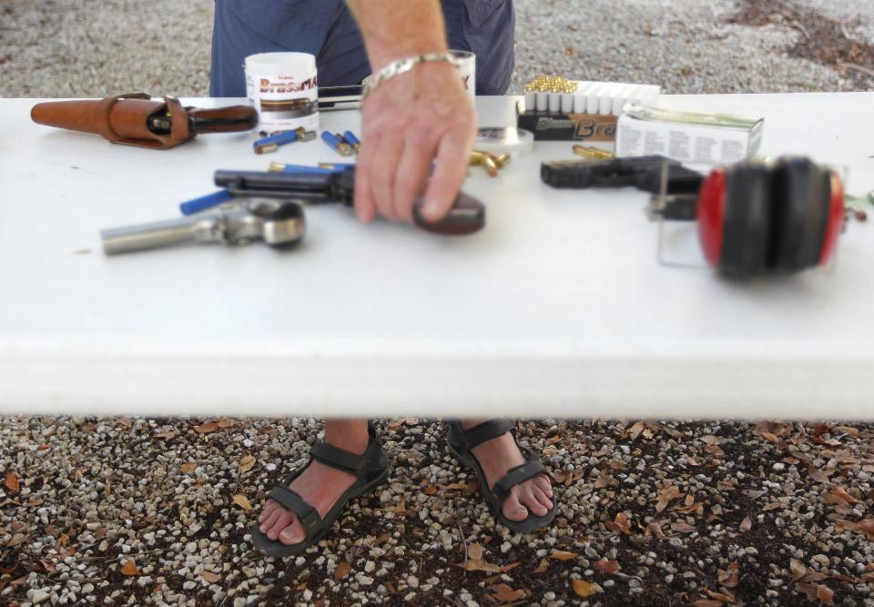 Doug Varrieur handles a handgun on a table at the firing range in the yard of his home in Big Pine Key in the Florida Keys March 5, 2014. Varrieur, 57, discovered a little-noticed part of Florida law which prohibits local governments from restricting gun rights in any way, and in December he set up a personal gun range on his property in a residential subdivision. Neighbors were outraged by the live gunfire, but their surprise was nothing compared to that of municipal leaders, who were shocked to realize there was nothing they could do about it. Picture taken March 5, 2014. REUTERS/Andrew Innerarity (UNITED STATES - Tags: SOCIETY)